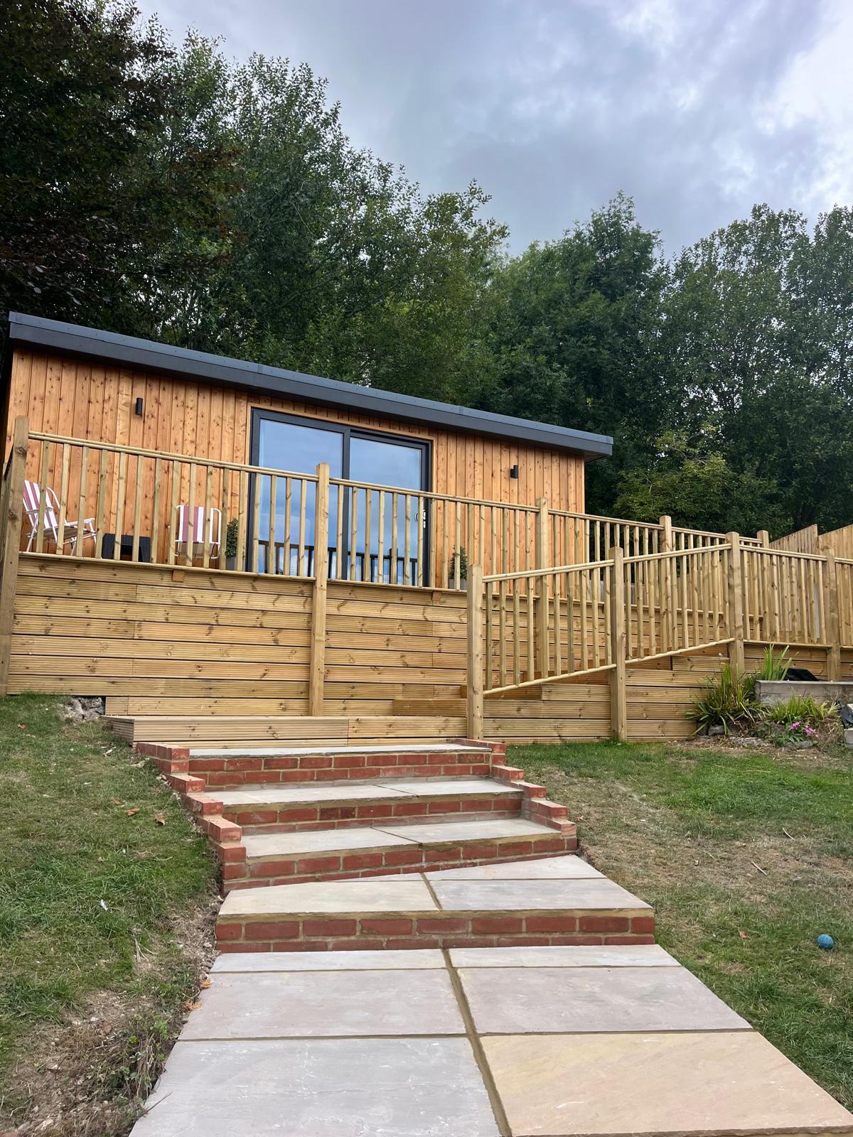 Raised timber decking, balustrade and sandstone steps built beside a garden lodge in Kent by SMB Groundworks and Servicing
