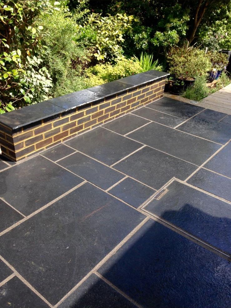 Black limestone patio with a brick seating wall built in a Kent garden