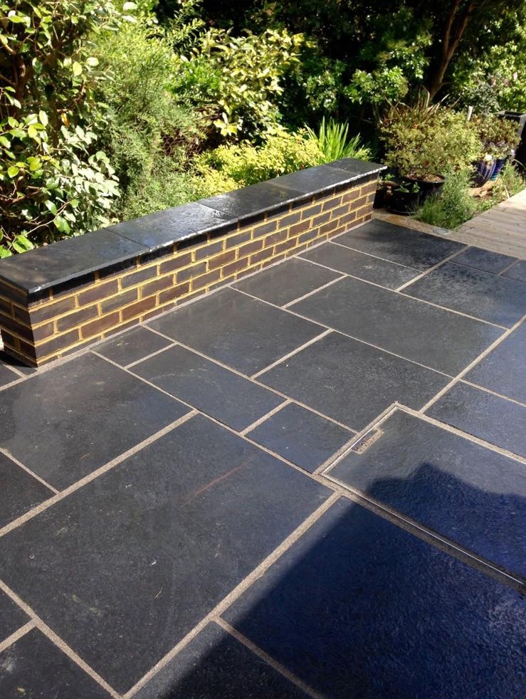 Black limestone patio with a brick seating wall in a Kent garden