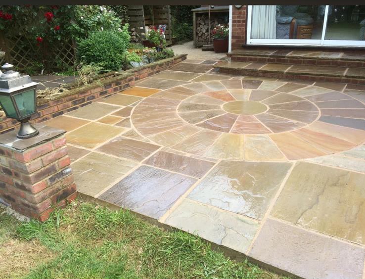 Indian sandstone patio with a circular stone feature and steps laid in a Kent garden