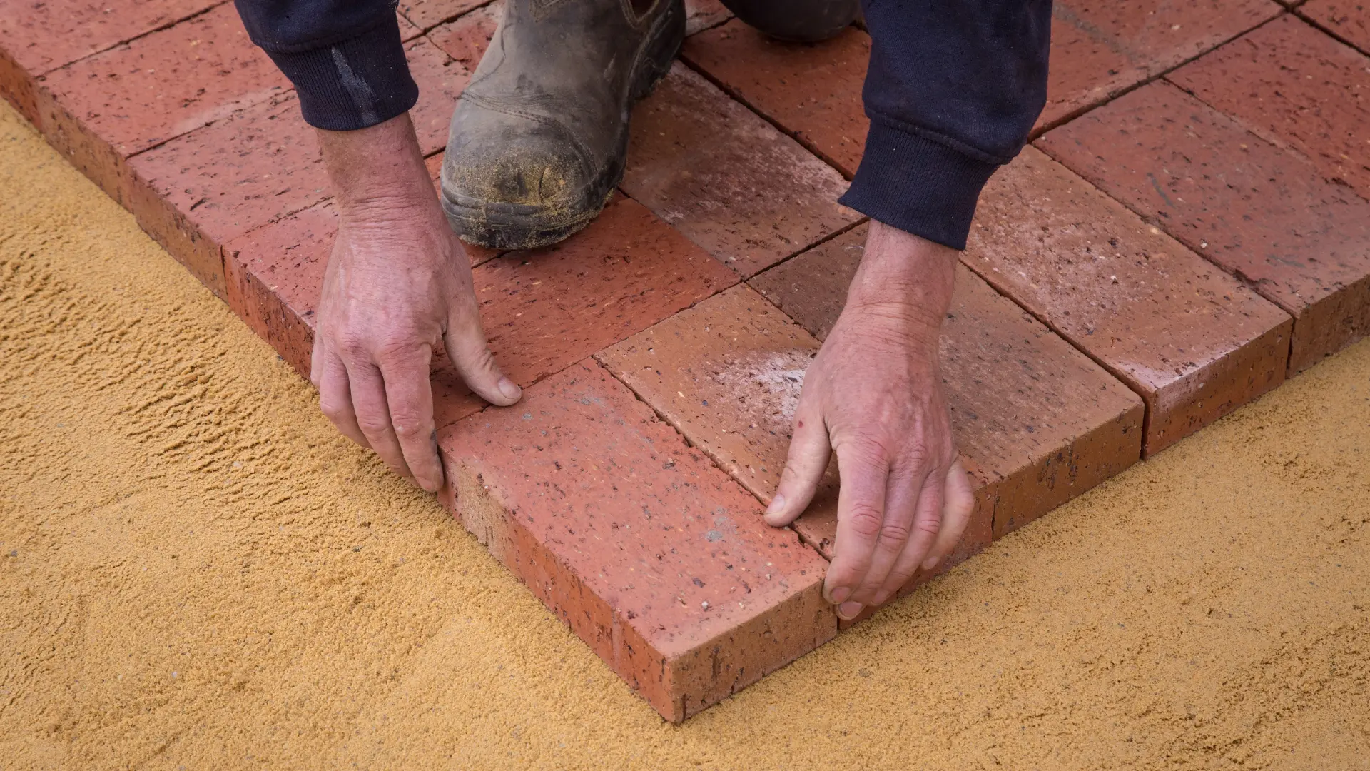 Brick paviors being bedded onto a prepared sand base during groundworks in Kent